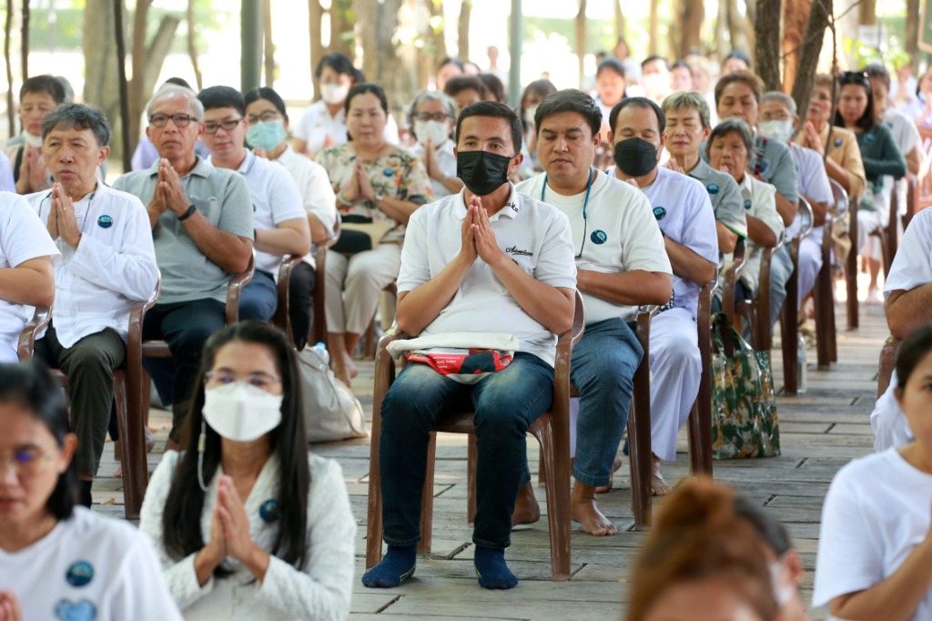 ผู้ร่วมปฏิบัติธรรมพนมมือเจริญภาวนาหน้าองค์พระพุทธรูปในถ้ำอมตธรรม