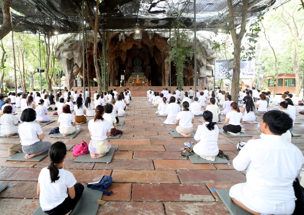 คณะสุภาพบุรุษและสุภาพสตรีสวมหน้ากากอนามัยนั่งสวดมนต์เจริญสมาธิ