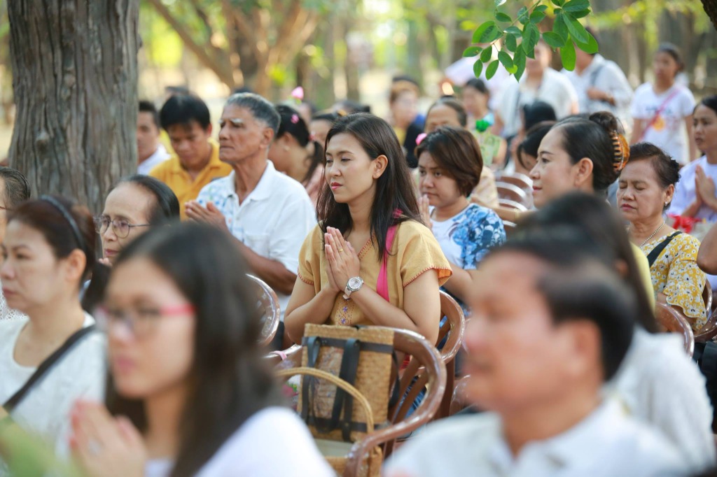 ผู้ปฏิบัติธรรมต่อแถวรับบริการอาหารโรงทานฟรีใต้ร่มสัปทนสีขาว