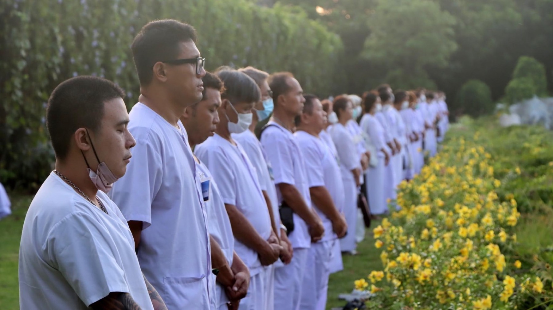 ผู้ปฏิบัติธรรมยืนสำรวมในแถวบริเวณสวน