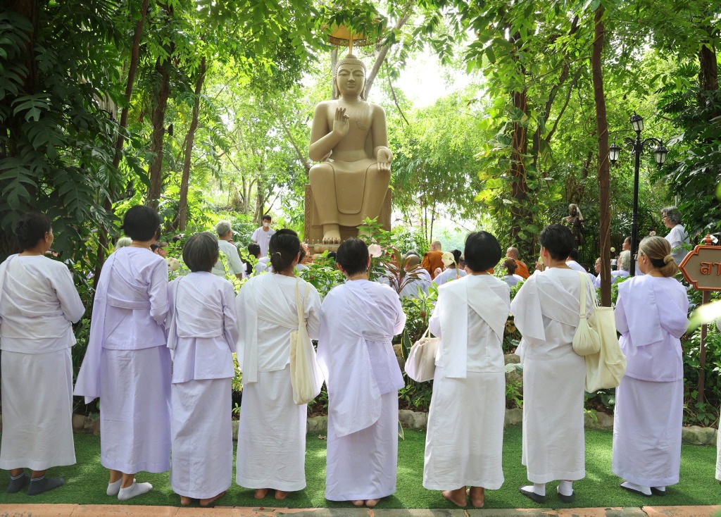 ผู้ปฏิบัติธรรมพนมมือสักการะพระพุทธปฏิมาในสวนพฤกษชาติ